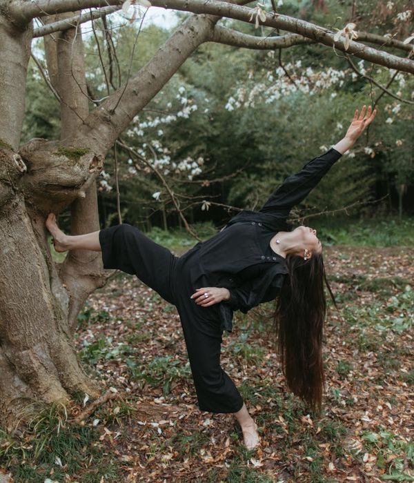 Woman performing a fluid yoga pose in a calm, dark environment.